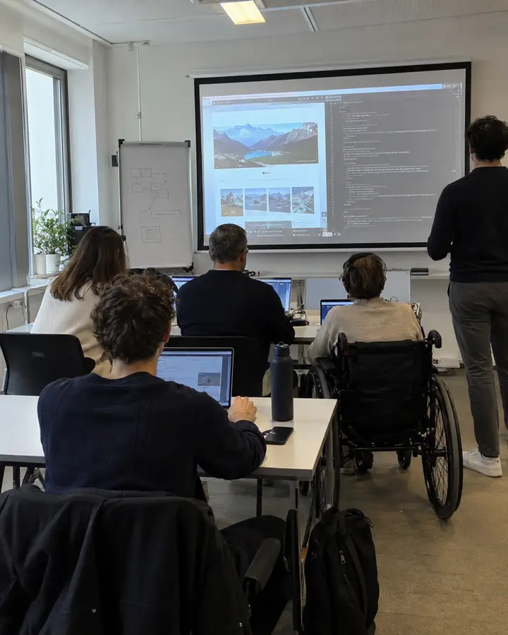 Schulung zur Barrierefreiheit mit Teilnehmenden an Laptops, eine Person im Rollstuhl, vorne die Leinwand