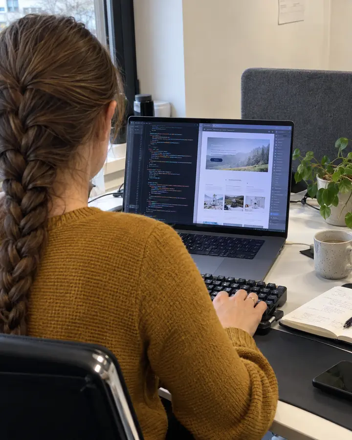 Entwicklerin baut eine Website im Code-Editor um, rechts daneben die Vorschau der Seite